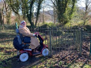Karen on her mobility scooter next to a kissing gate, which she can't fit through