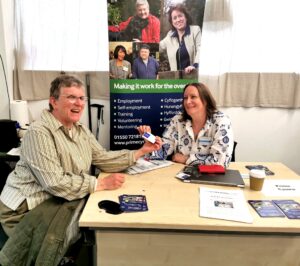 Karen smiles whilst handing her business card to Tracy Eynon at Ystradgynlais Job Centre