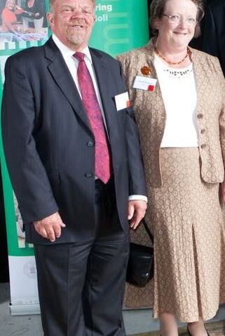 Hugh and Ann smile with a PRIME Cymru banner in the background